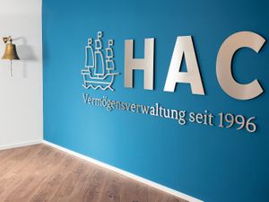 Firmenlogo aus gebürstetem Edelstahl an Wandfläche