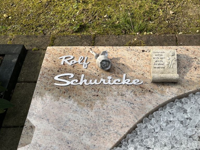 Grabschrift Rolf Schuricke aus gebürstetem Edelstahl auf poliertem Grabstein mit Deko