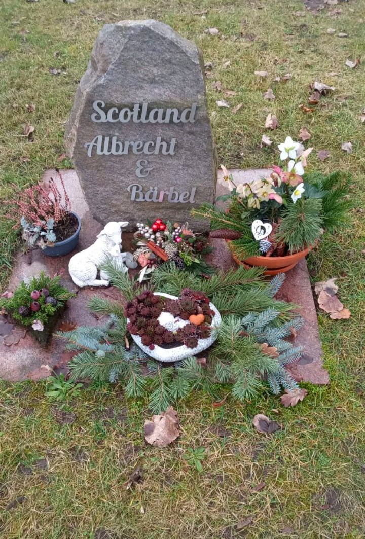 Findling mit Grabschrift Scotland, Albrecht & Bärbel aus gebürstetem Edelstahl und Blumenschmuck