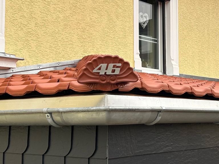 Gebürstete Edelstahl-Hausnummer auf einem roten Ziegeldach mit der Zahl 46