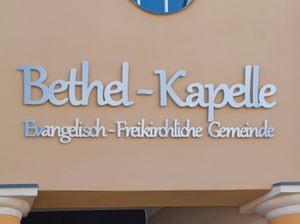 Edelstahl-Schriftzug mit Abstandshaltern an der Fassade