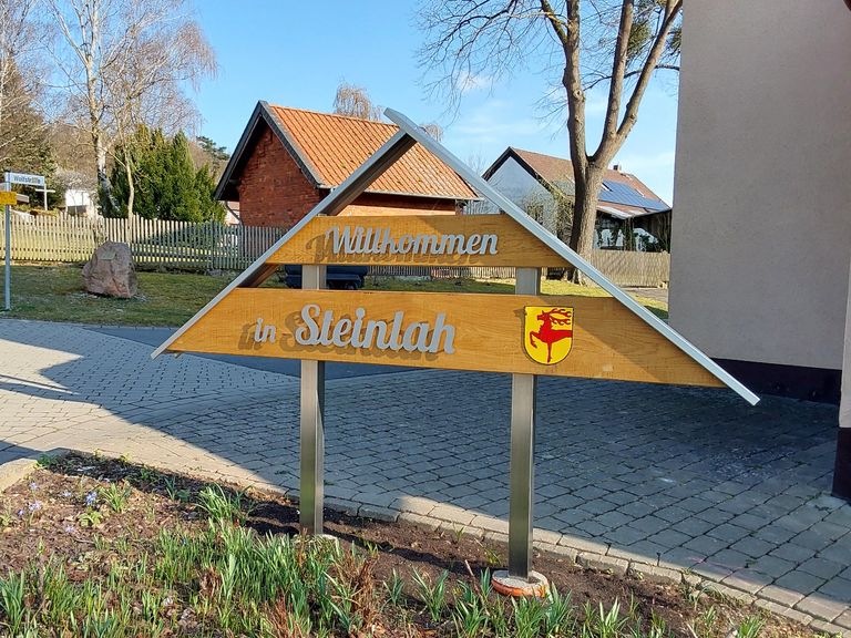 Ortseingangsschild Willkommen in Steinlah mit Edelstahlbeschriftung auf Holzpaneelen