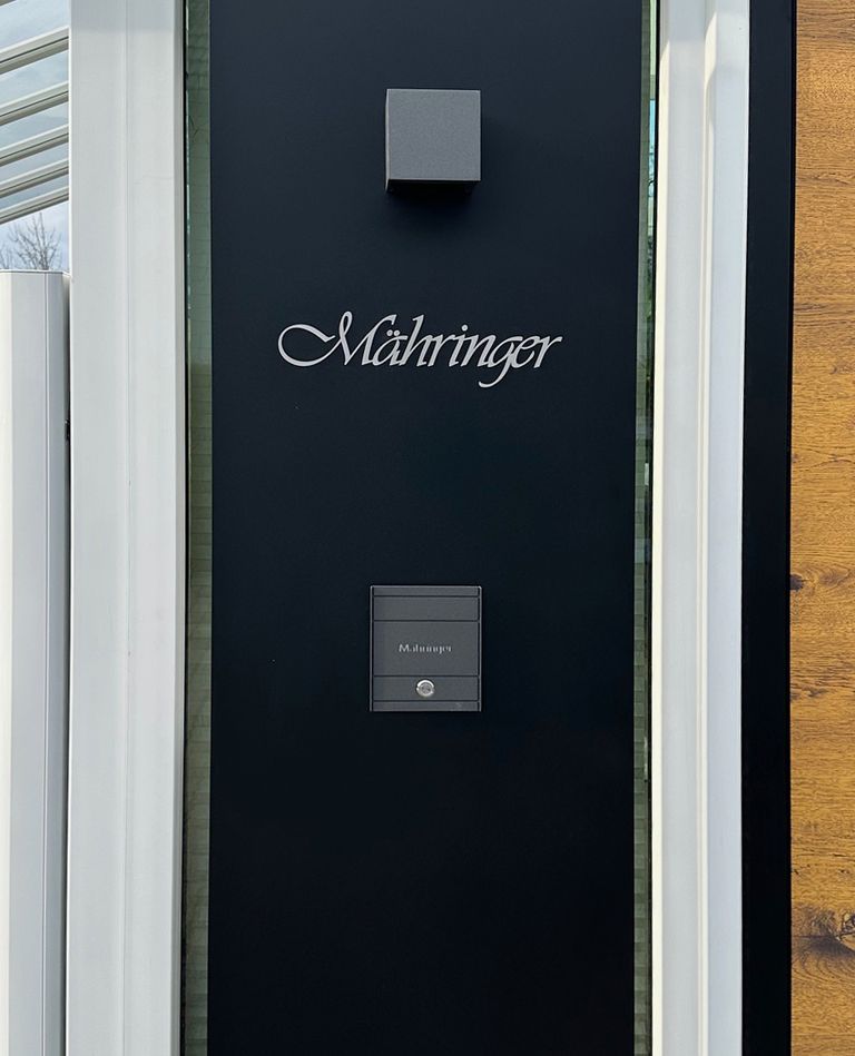 Schriftzug Mähringer in eleganter Schrift auf schwarzer Fläche neben der Haustür