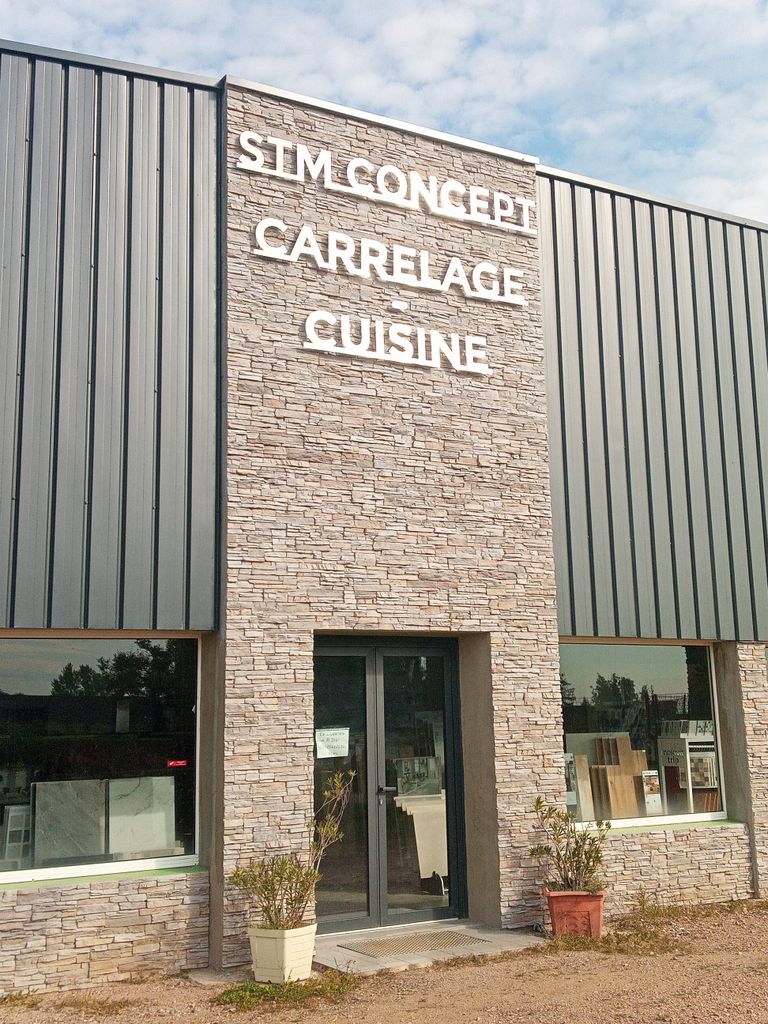 Weiße Schriftzüge STM Concept, Carrelage und Cuisine an Fassade mit Steinoptik