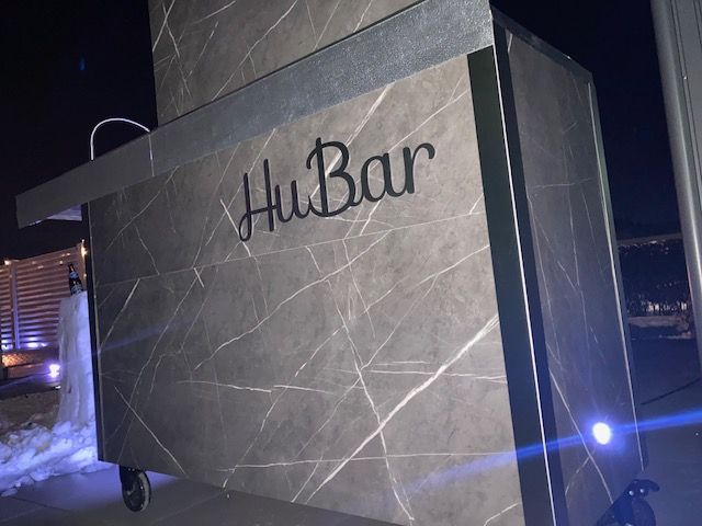 Schriftzug HuBar aus schwarzem Edelstahl auf einer mobilen Theke bei Nacht